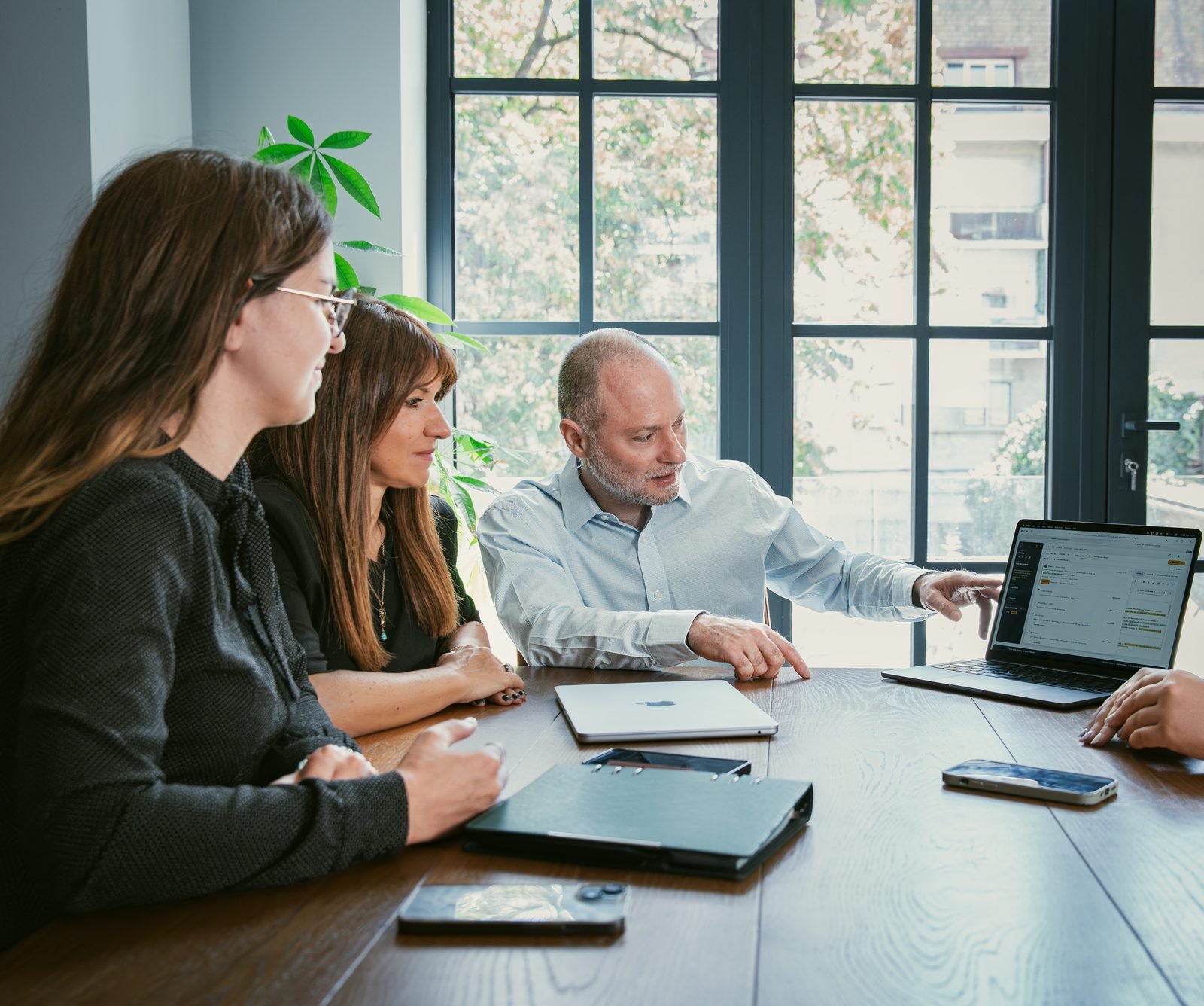 Three colleagues reviewing a matter plan on one laptop.