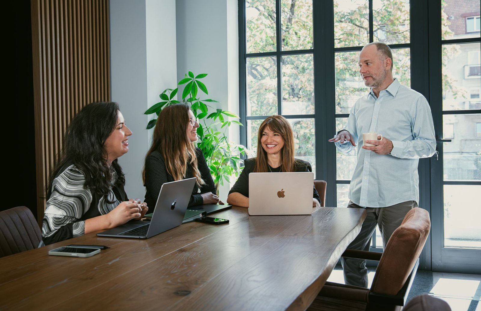 The Wisanna team in a meeting room: three colleagues at a table with laptops and the founder standing by the window.